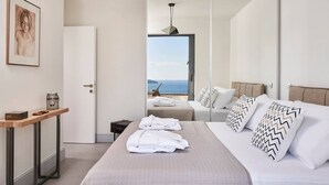 Een moderne hotelkamer met een groot bed, nachtkastje, bureau en uitzicht op de zee.
