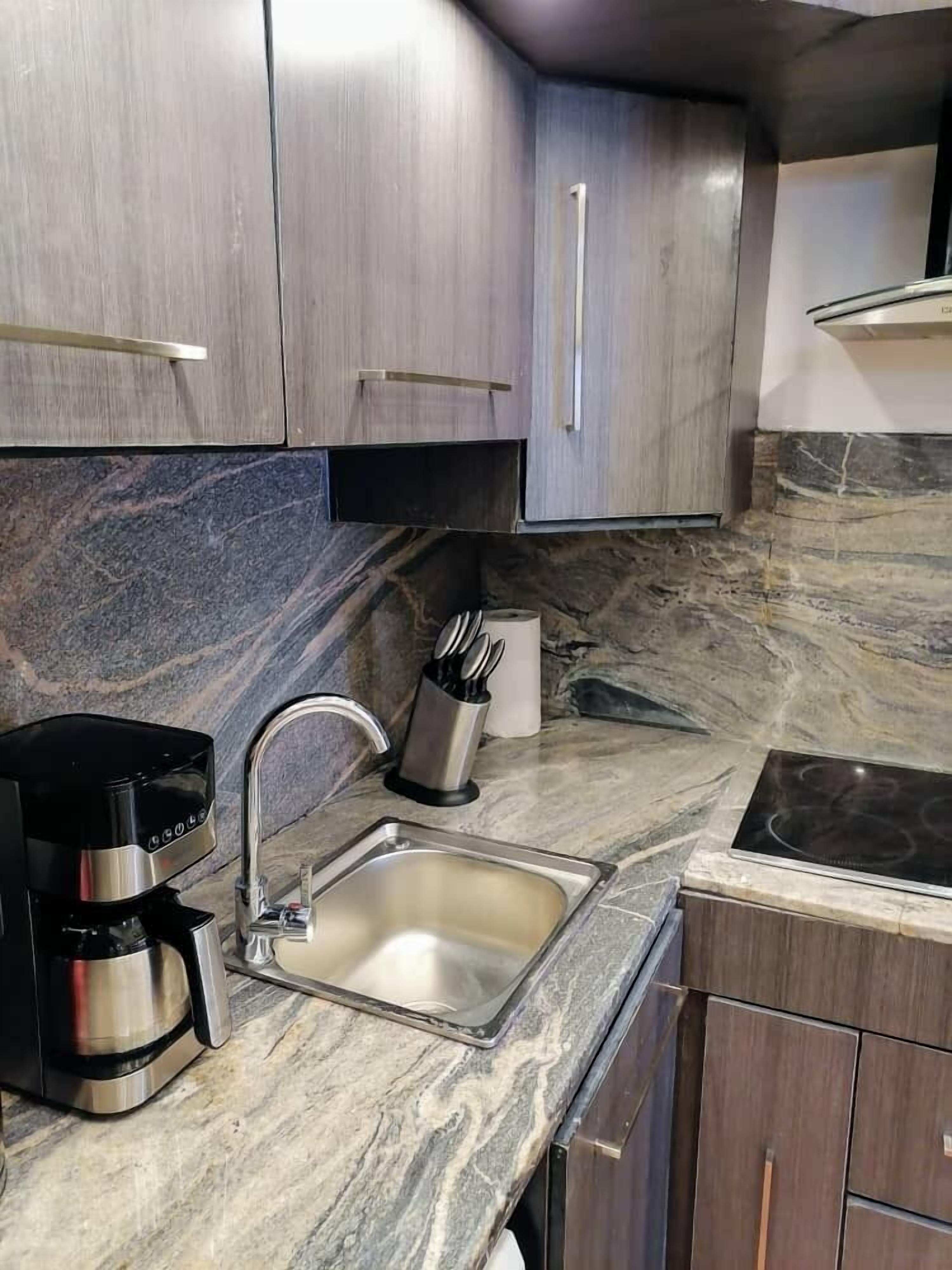A modern kitchen with a stainless steel sink, a coffee maker, and a stove.