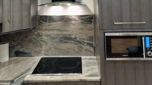 A modern kitchen with a built-in stove, a microwave, and a dark wooden cabinet. - Appartement Meublé VIP Douala Bonapriso (Douala)