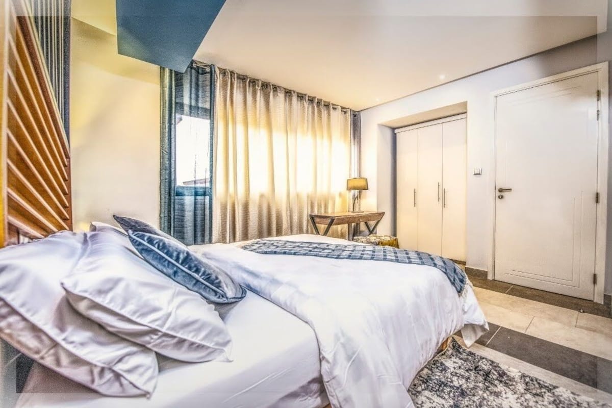 A hotel room with a bed, curtains, a desk, and a wardrobe.
