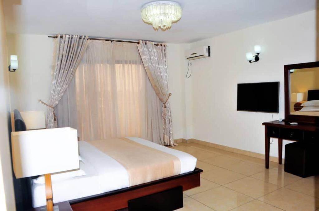 Une chambre d’hôtel avec un lit, un bureau, une télévision et un lustre.