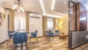 A modern hotel room with a dining area, a sofa, and a large mirror. - Appartement Meublé VIP Douala Bonapriso (Douala)
