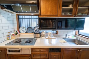 A kitchen with a stove, microwave, sink, and cabinets. - Villa Traditional Designer House Oyama (Tokyo)