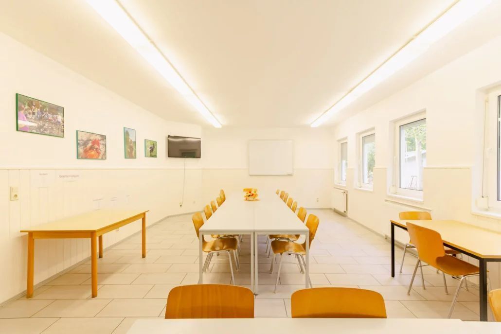 A conference room with a long table and chairs, white walls, and framed pictures.