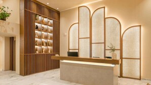 A reception desk with a modern design, a wooden panel wall with shelves, and a traditional screen door.