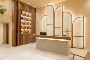 A reception desk with a modern design, a wooden panel wall with shelves, and a traditional screen door.