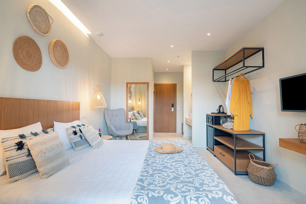 Una habitación de hotel moderna con una cama, una silla, un televisor y una pequeña zona de escritorio.