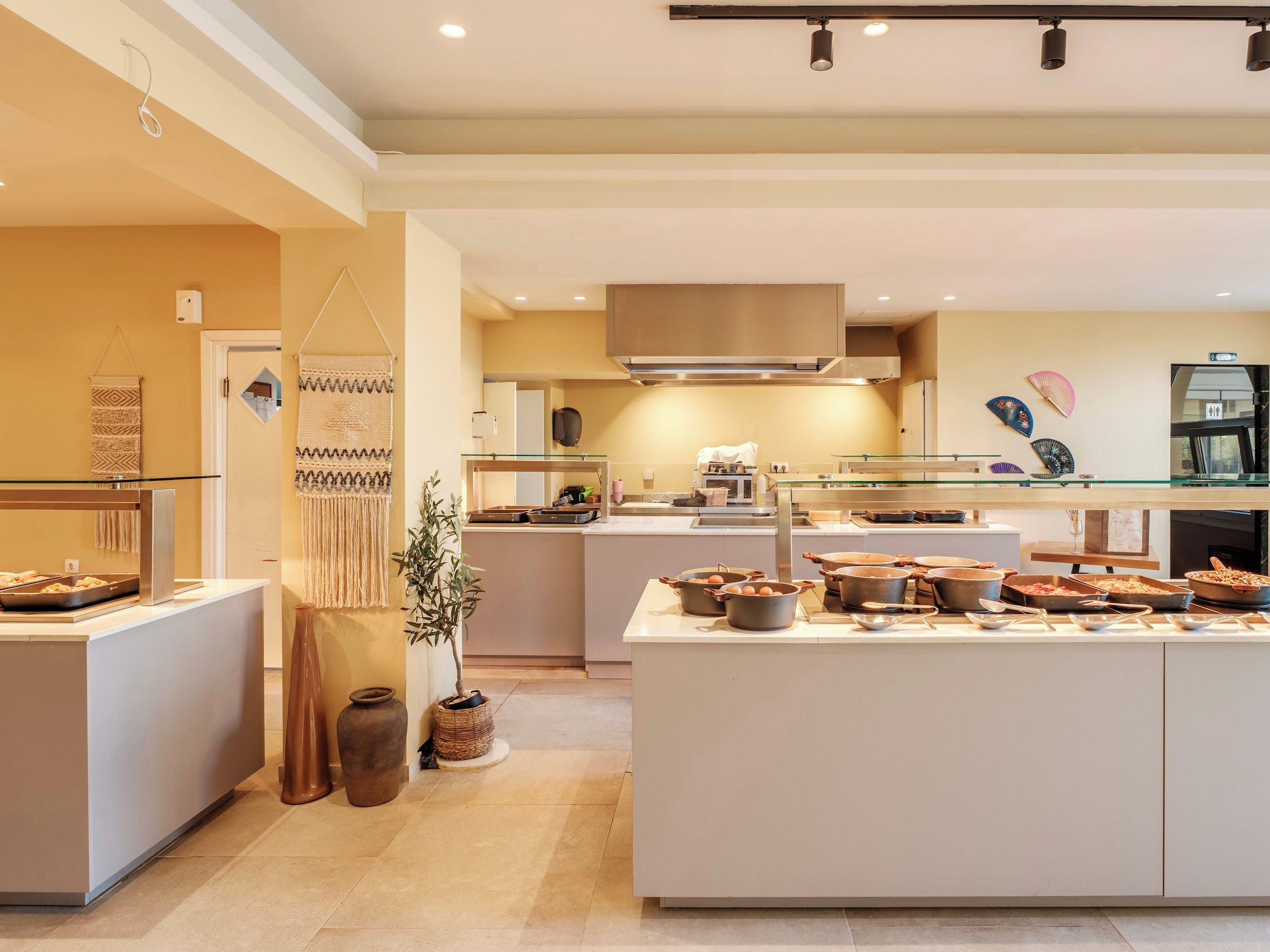 Een moderne keuken met een centraal eiland, een hanglamp en een ventilator aan de muur.