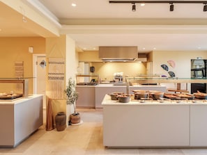 Una cocina moderna con una isla central, una lámpara colgante y un ventilador de pared.
