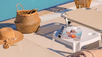Un salon de bord de piscine avec un panier tressé, un chapeau et un magazine sur un transat.
