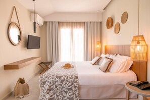 Habitació d'hotel amb un llit, una televisió, una làmpada penjant i un mirall a la paret.