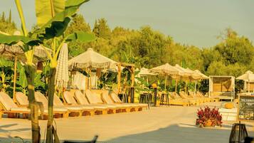 Un espace aménagé au bord de la piscine, avec des chaises longues, des parasols et un panneau d’affichage.