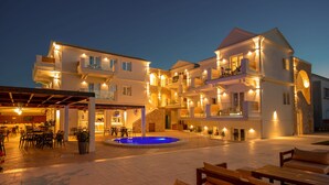 A multi-story hotel with outdoor seating, a swimming pool, and a covered patio area.