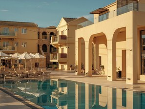 Un espace piscine d’hôtel avec des chaises longues, des parasols et une piscine à eau claire.