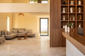 Un salon moderne avec un canapé d’angle, une table basse en bois et une bibliothèque intégrée en bois, agrémentée d’objets décoratifs.