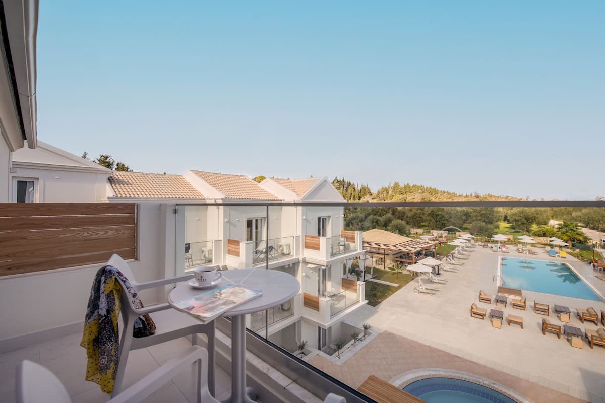 Un balcón con mesa, sillas y vistas a una piscina y zona de estar al aire libre.