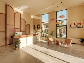A reception area with a reception desk, seating, large windows, and artwork.