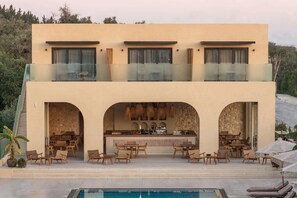Ein zweistöckiges Gebäude mit Barbereich, Außenbereich und einem Pool.