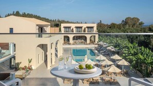 A modern hotel with a pool, outdoor seating, and a view of the surrounding landscape.