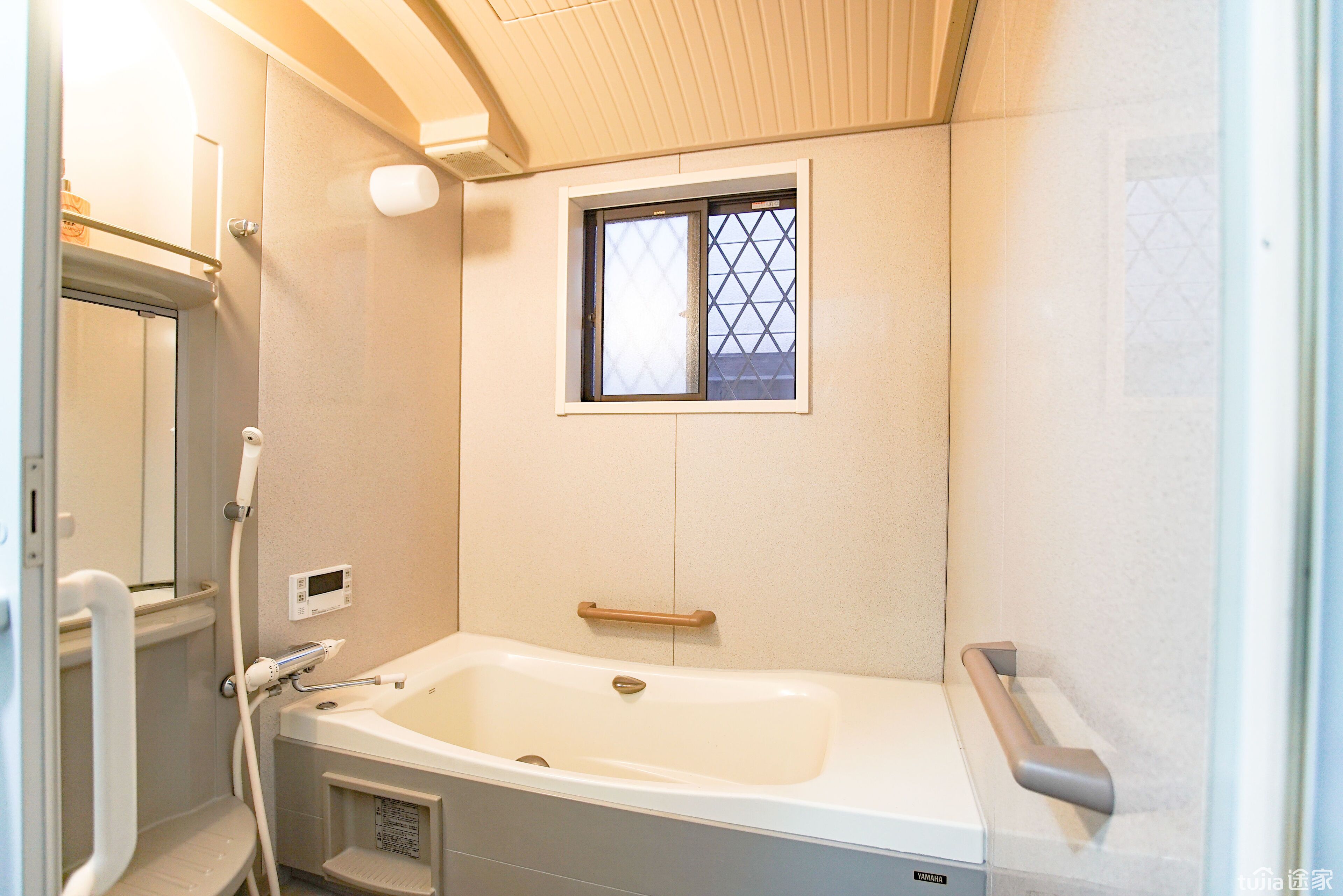 Une salle de bain avec une baignoire, une fenêtre et une barre d’appui.