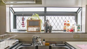 A kitchen with a window, a sink, and various items on the counter. - Villa Traditional Designer House Shin Itabashi (Tokyo)