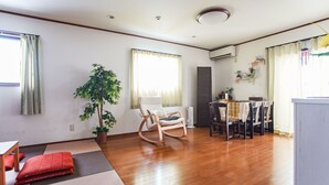 A spacious living area with a wooden floor, a rocking chair, a dining table with chairs, and a potted plant. - Villa Traditional Designer House Shin Itabashi (Tokyo)