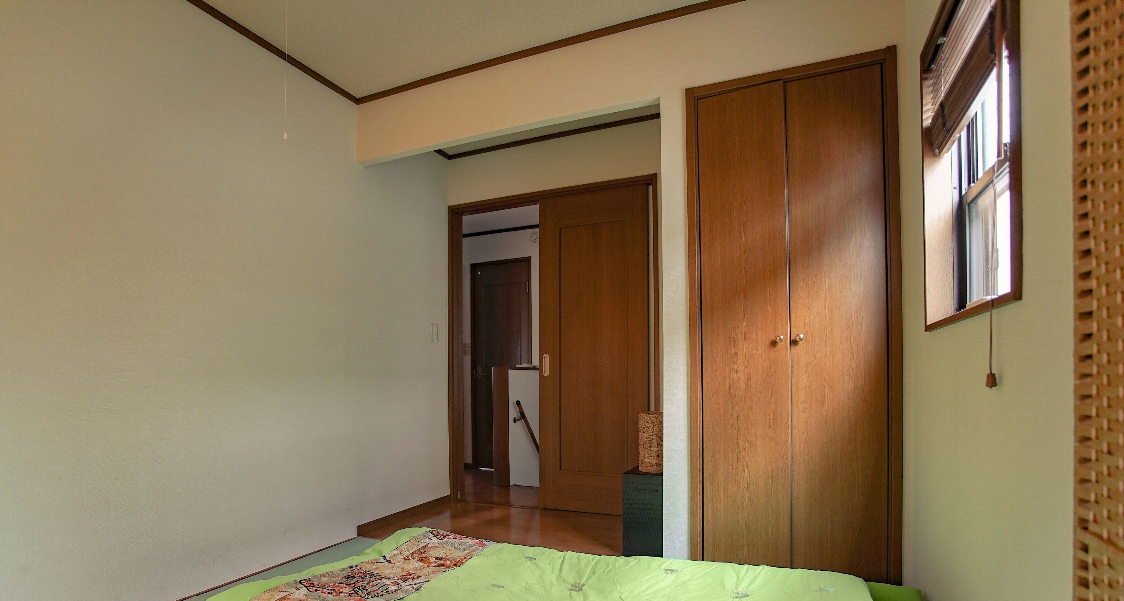Un dormitorio con una cama, un armario de madera y una puerta que da a otra habitación.