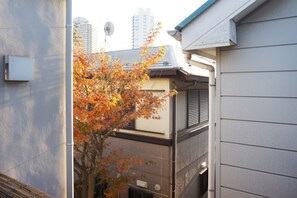 A residential building with a satellite dish, a tree with autumn leaves, and a neighboring high-rise building. - Villa Traditional Designer House Shin Itabashi (Tokyo)