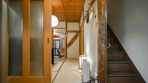 Un intérieur japonais traditionnel avec un sol recouvert de tatamis, un escalier en bois et une porte coulissante.