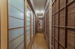 A narrow hallway with traditional sliding doors on both sides, wooden flooring, and a small table with items in the center. - Villa Traditional Designer House Itabashi (Tokyo)