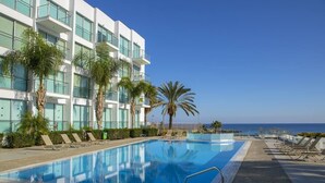 Ett modernt hotell med pool, palmer och utsikt över havet.