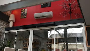 A modern interior with a red accent wall, a skylight, and a wine rack visible through a glass door.