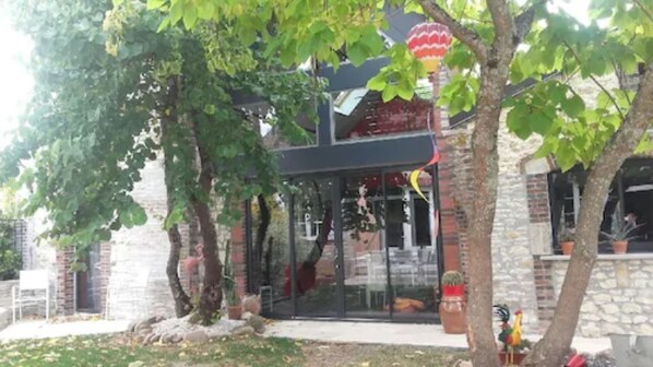 A building with a glass facade, stone walls, and a red roof. There are trees in front of the building. - Le Rouge & Blanc (Saint-Maurice-le-Vieil)