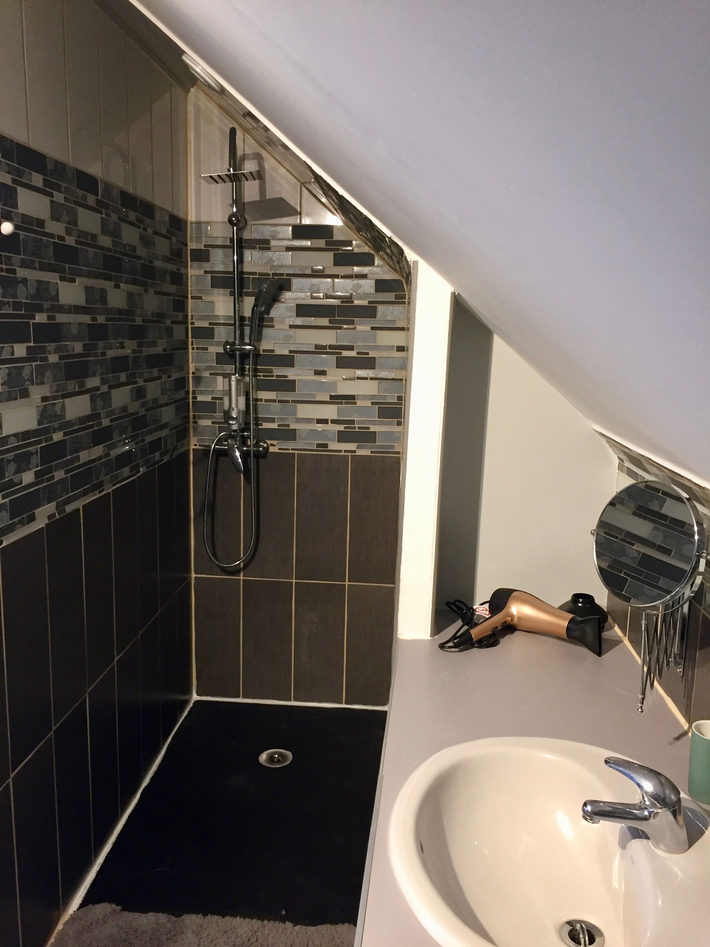 Ein Badezimmer mit Dusche, Waschbecken und Spiegel.