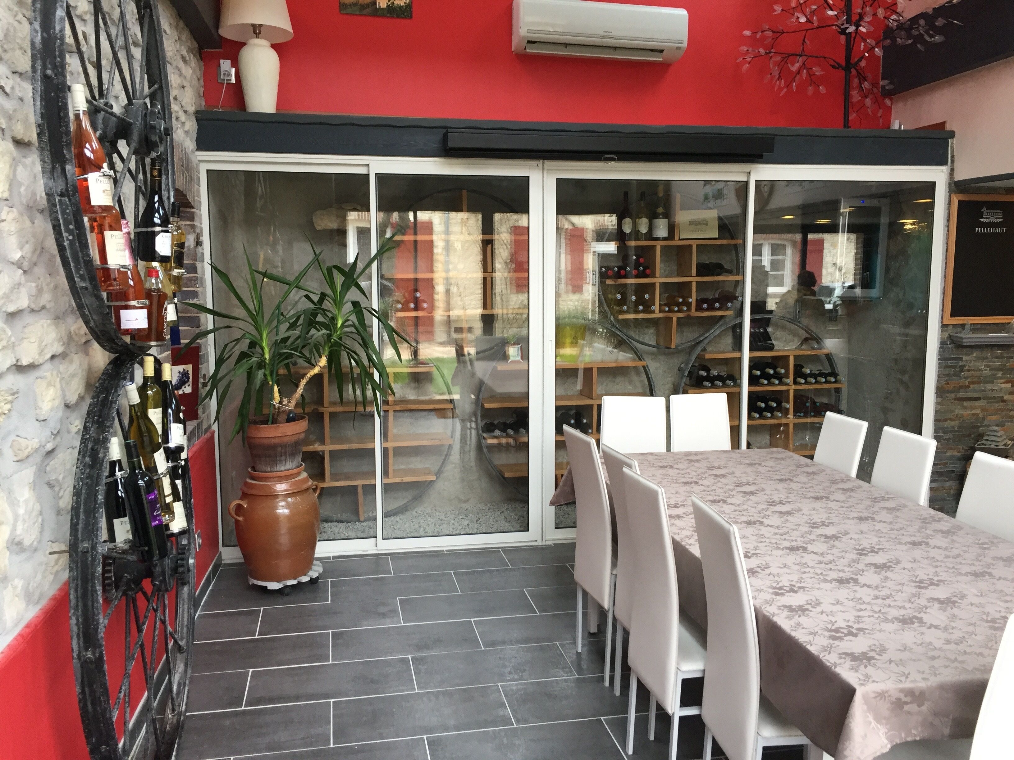 A restaurant with a red exterior, a glass door entrance, a tiled floor, a table with chairs, and a potted plant.