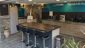 A modern kitchen with a central island, bar stools, a pizza oven, and a microwave. - Le Rouge & Blanc (Saint-Maurice-le-Vieil)