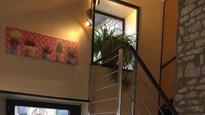 A modern interior with a staircase, a glass door leading to an outdoor area, and a wall-mounted plant. - Le Rouge & Blanc (Saint-Maurice-le-Vieil)