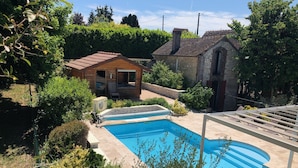 A swimming pool with a wooden deck, surrounded by greenery and a small wooden structure. - Le Rouge & Blanc (Saint-Maurice-le-Vieil)