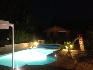 A swimming pool with a slide and a small house in the background. - Le Rouge & Blanc (Saint-Maurice-le-Vieil)