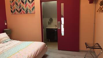 A bedroom with a bed, a door leading to a bathroom, and a mirror on the wall.