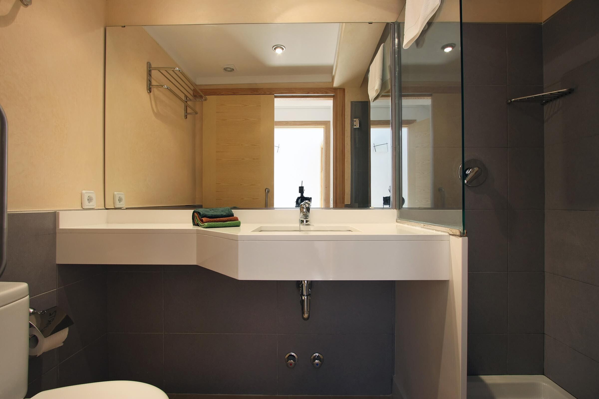 A modern bathroom with a white sink, a glass shower enclosure, and a visible toilet.