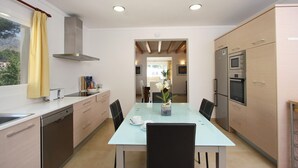 A modern kitchen with a dining table, chairs, and a view of the dining area. - MEDINA. Modern villa just 325 m from crystal clear beaches (Cala San Vicente)