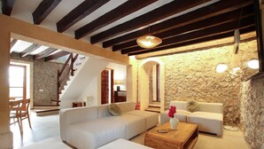 A spacious living area with a stone wall, a wooden staircase, and a modern sofa set. - ALORDES. Tradition and views next to Pollensa (Pollensa)