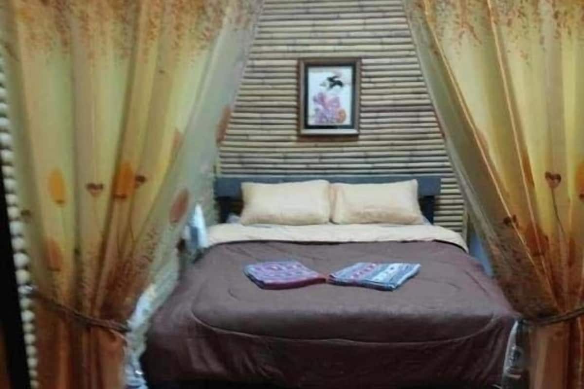Ein Bett mit brauner Bettdecke, zwei Kissen und ein gerahmtes Bild an der Wand dahinter.