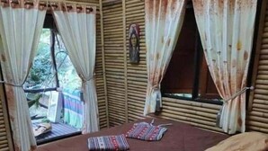 Une chambre avec un lit, deux oreillers et une fenêtre avec des rideaux.