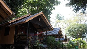 Une rangée de cabanes en bois aux toits de chaume, entourées d’une végétation luxuriante et de palmiers.