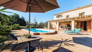 A pool area with a stone building, outdoor seating, and a windmill in the background.