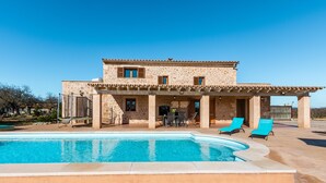 A two-story building with a swimming pool, outdoor seating, and a covered patio area.