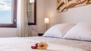 A neatly made bed with white linens and a single flower on the bedspread. - Cas FRARE. Respecting roots with style (Buger)