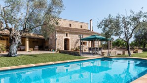 A stone building with a swimming pool, outdoor seating, and a covered patio area. - Cas FRARE. Respecting roots with style (Buger)